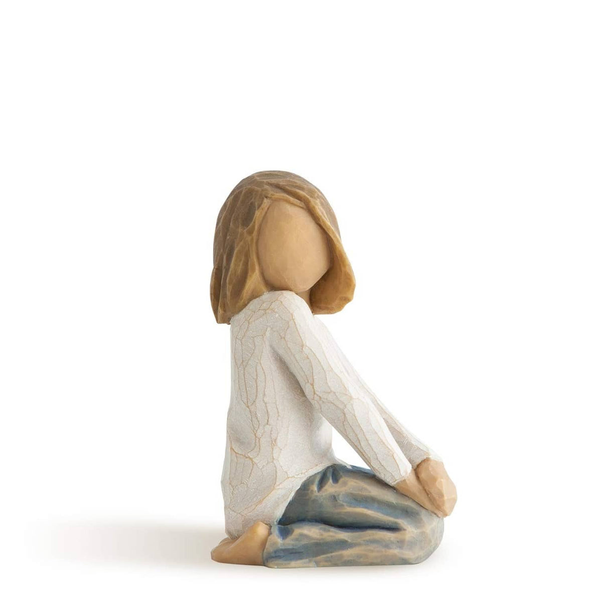 Seated child figurine with brown hair, white robe, and blue-gray blanket, kneeling.