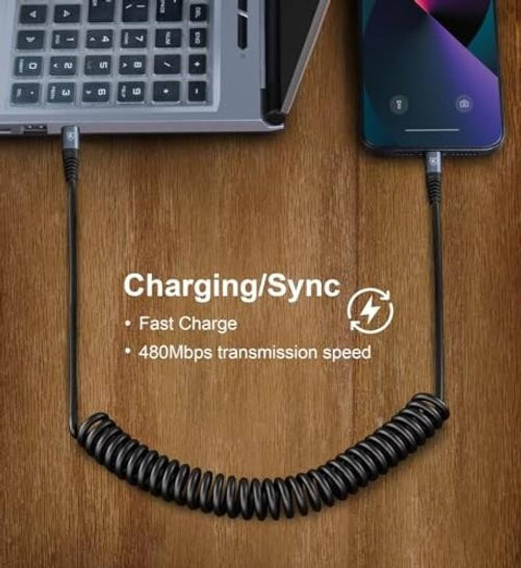 Black USB-C to USB-C coiled charging/sync cable on wooden desk