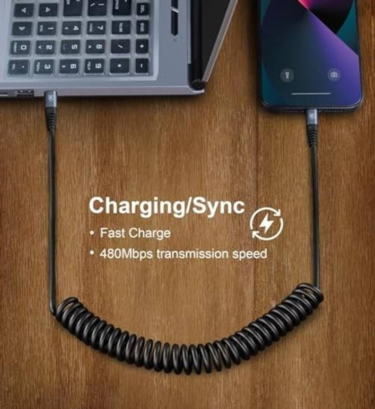 Black USB-C to USB-C coiled charging/sync cable on wooden desk