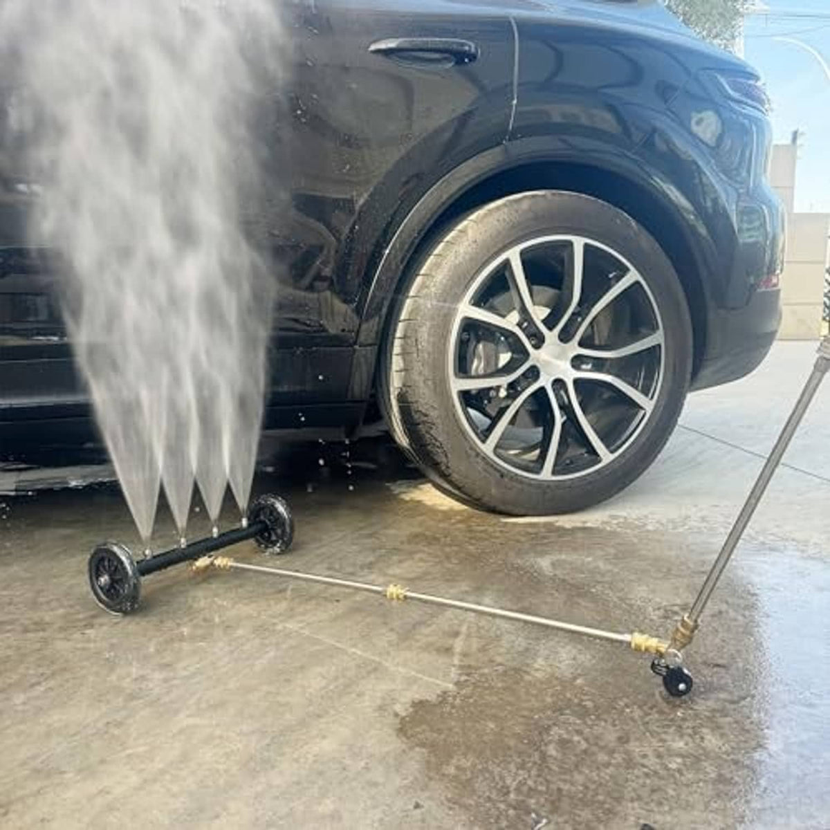 Undercarriage cleaner with rotating nozzle spraying under a vehicle near the front wheel