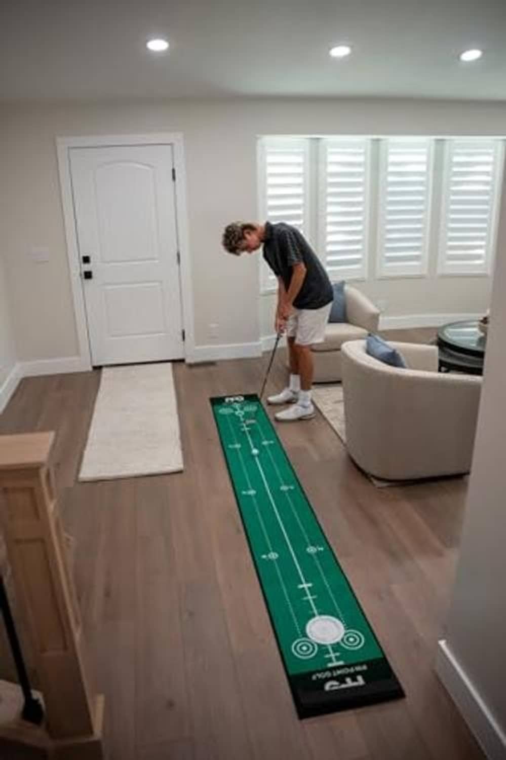 Indoor green putting mat with distance markers laid on hardwood floor