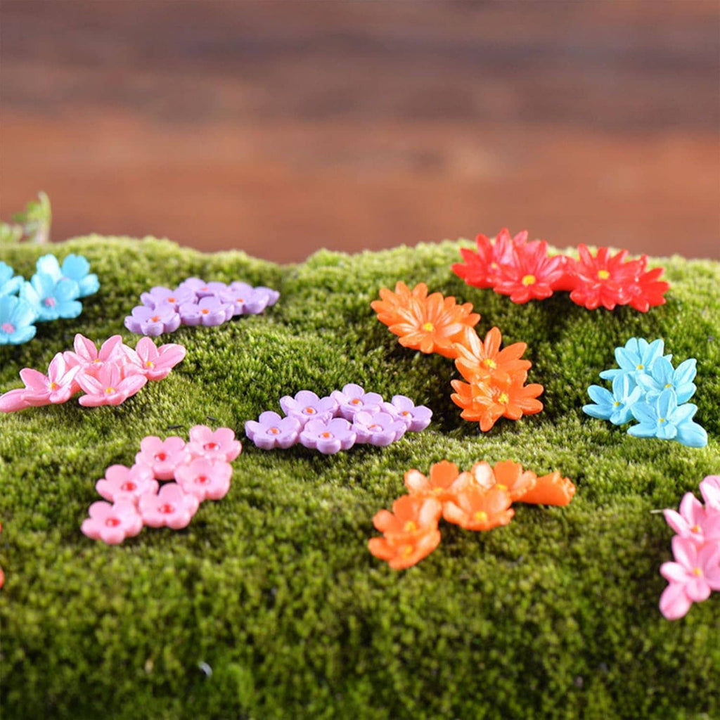 Mini resin flowers scattered on green moss, with pink, orange, purple, and blue blooms