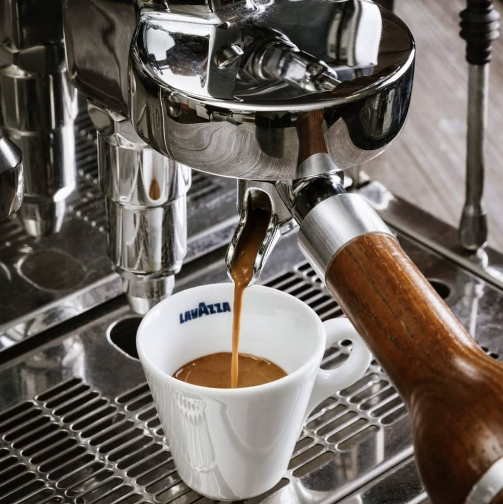 Espresso cup with crema beneath chrome espresso machine spout