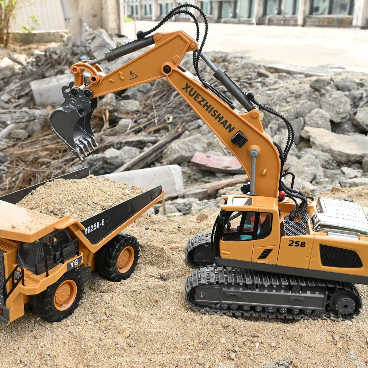 RC tracked excavator toy with metal bucket on gravel, plus another toy truck beside it