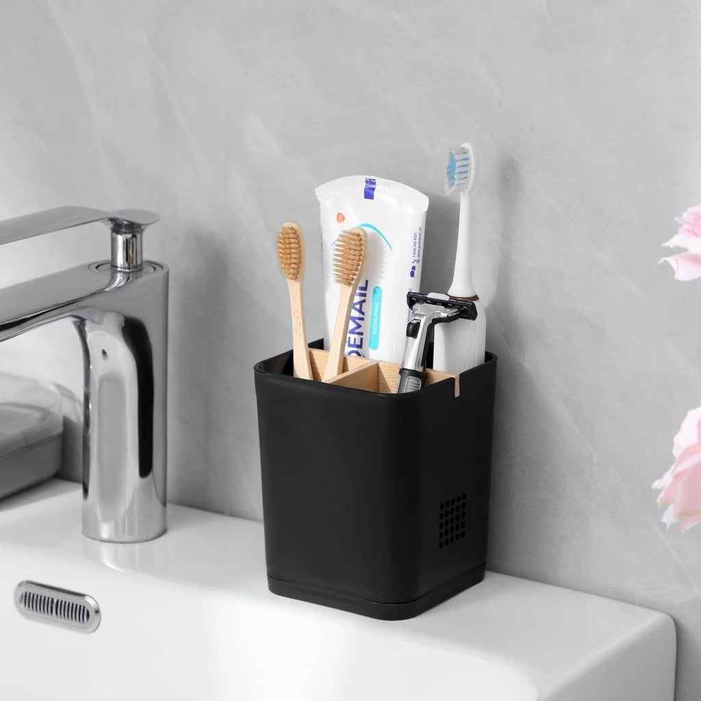Black 3-slot toothbrush holder on a vanity counter, holding three toothbrushes
