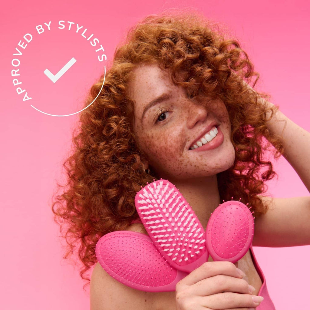Pink detangling brush set with oval pads and pin bristles, held for styling