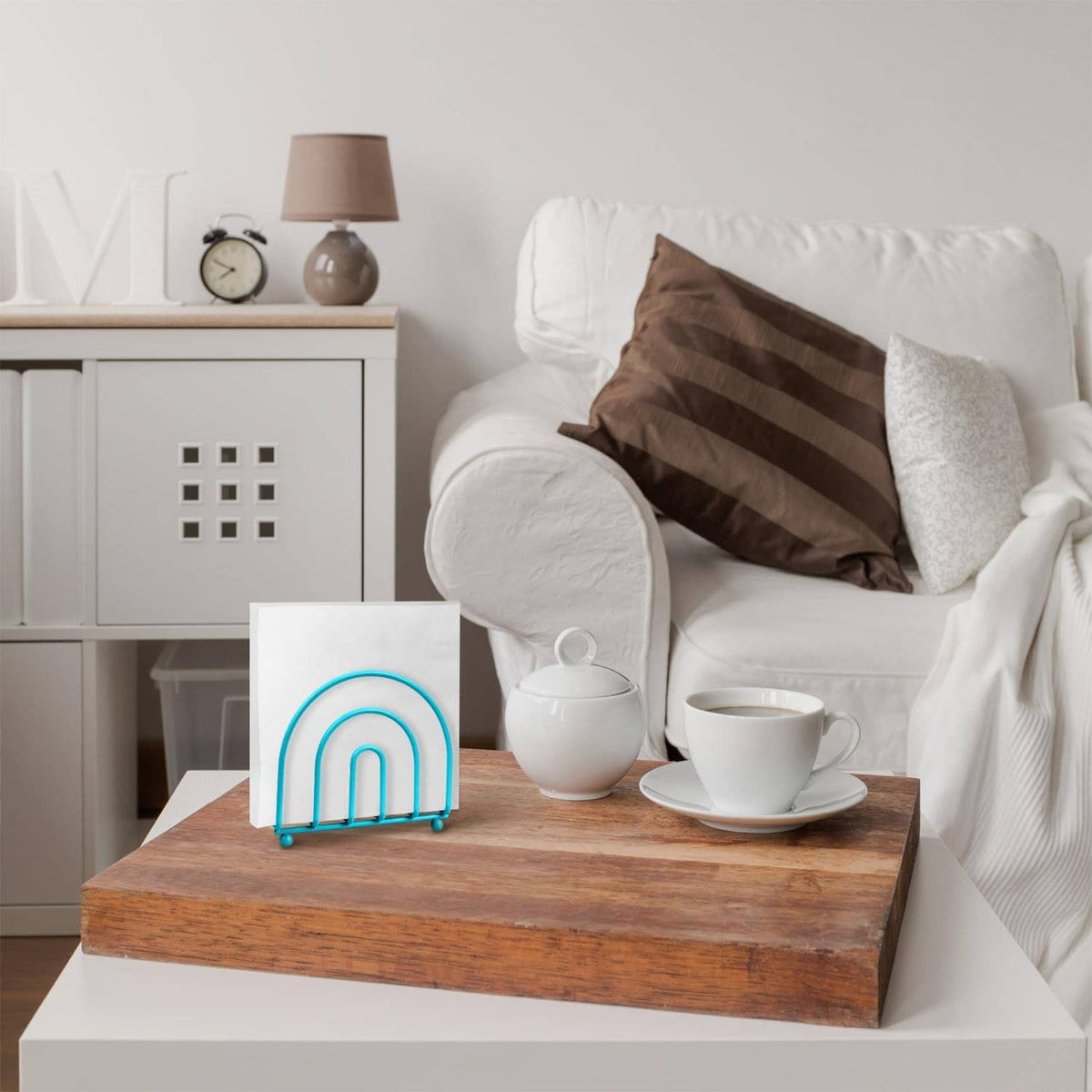 Turquoise arc napkin holder with rounded feet on a tabletop.