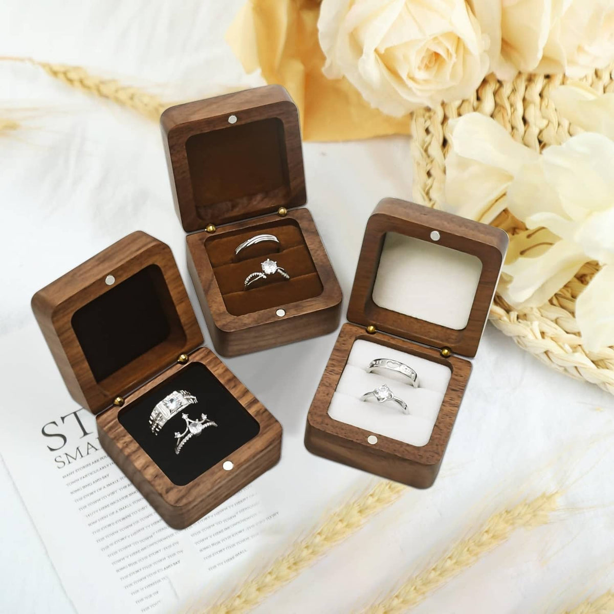 Collection of small dark wooden ring boxes with black velvet inserts and silver rings