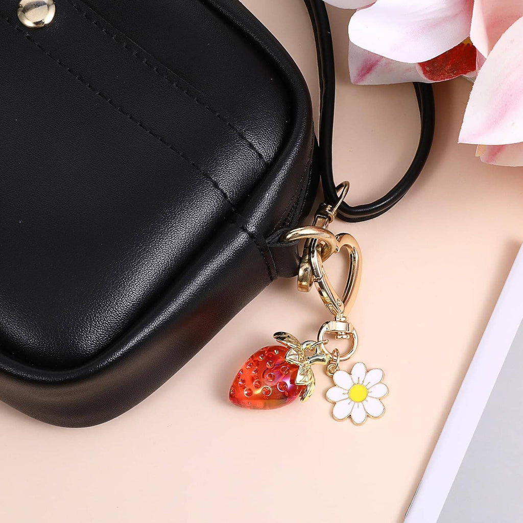 Strawberry heart keychain charm with white daisy, attached to a black bag strap