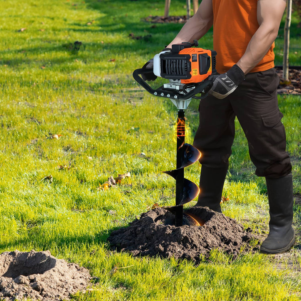 Gas post hole digger auger spiral bit drilling into ground near grass