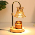 Electric candle warmer lamp with amber glass shade, gold stem, round wood base and candle jar.
