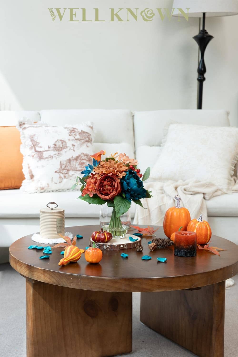 Teal and orange artificial flower bouquet in clear glass vase on tabletop