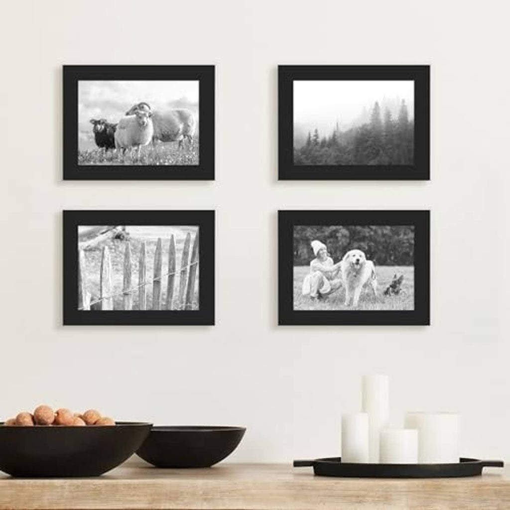 Four black wood picture frames displayed on wall with landscape photo prints