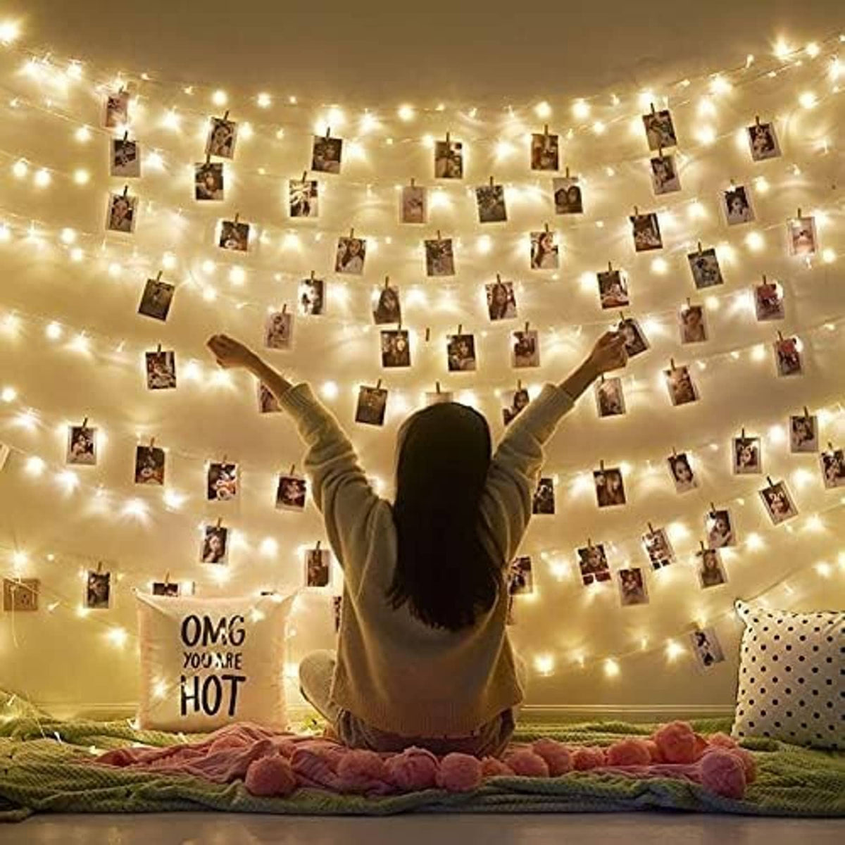 Small photos clipped up with wooden clothespins on a string light display