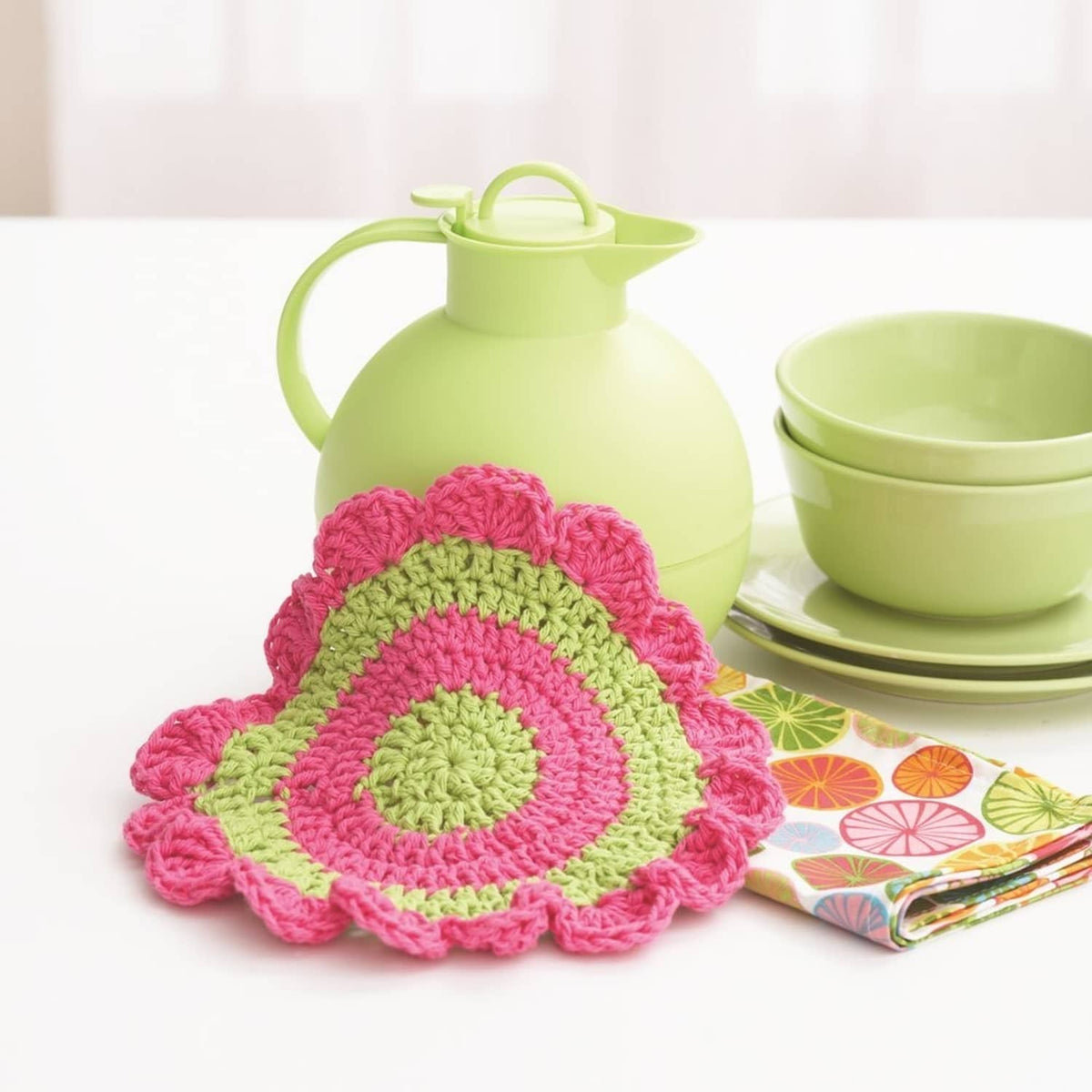 Crocheted round pot holder with pink scalloped edge and green center