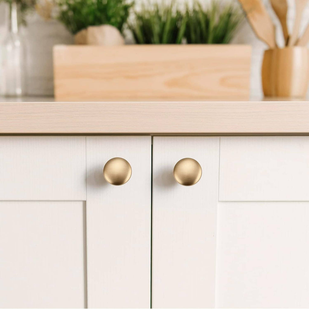 Pair of champagne bronze round cabinet knobs on white cabinet drawers