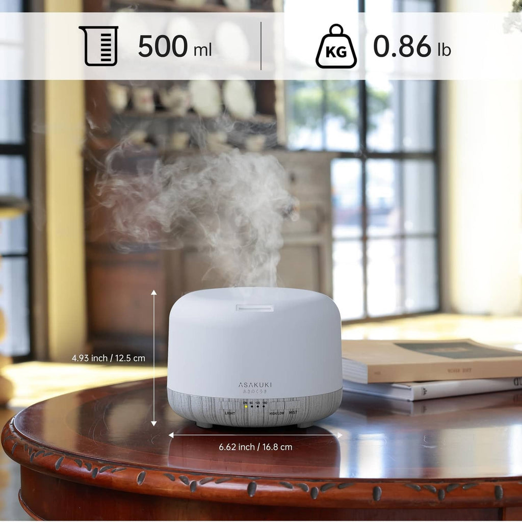 White essential oil diffuser on a table releasing mist with size indicators