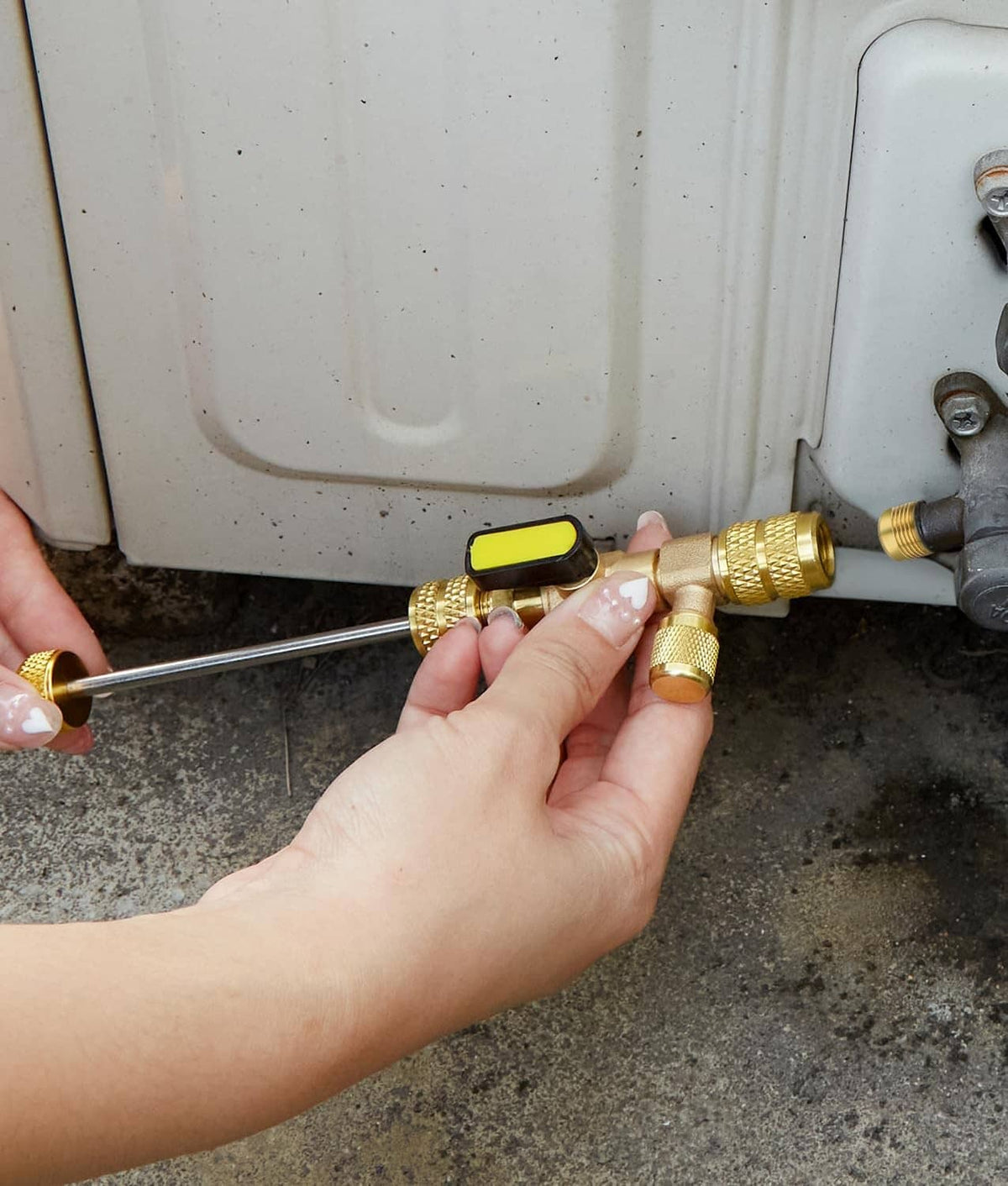 Hand using brass valve core removal tool with long rod and black lever cap on unit