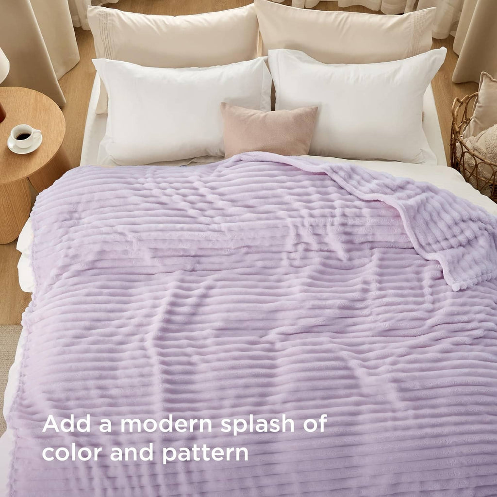 Lavender fog textured throw blanket draped across a bed