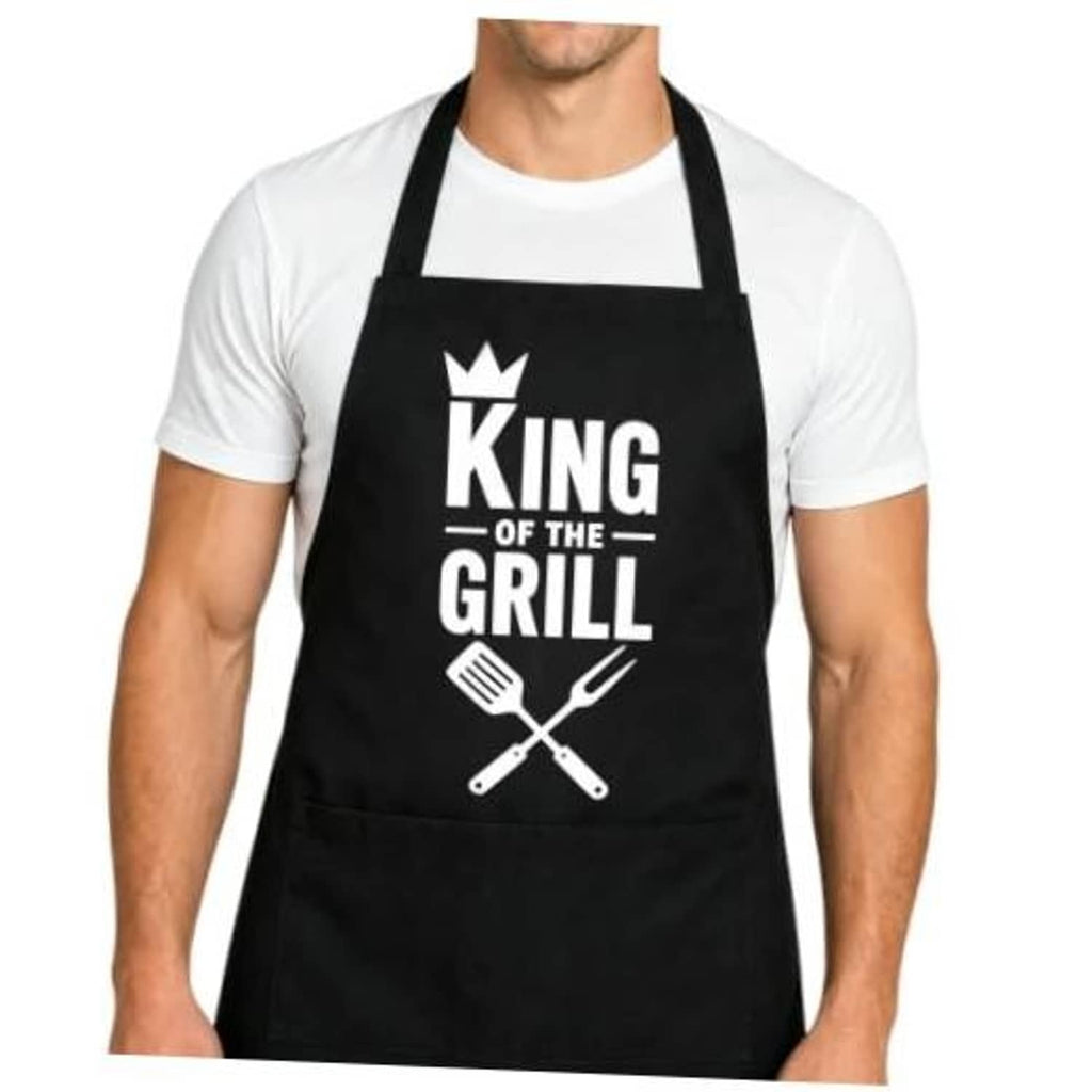 Black BBQ apron on a model, 'King of the Grill' crown logo with crossed grilling tools