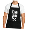 Black BBQ apron on a model, 'King of the Grill' crown logo with crossed grilling tools