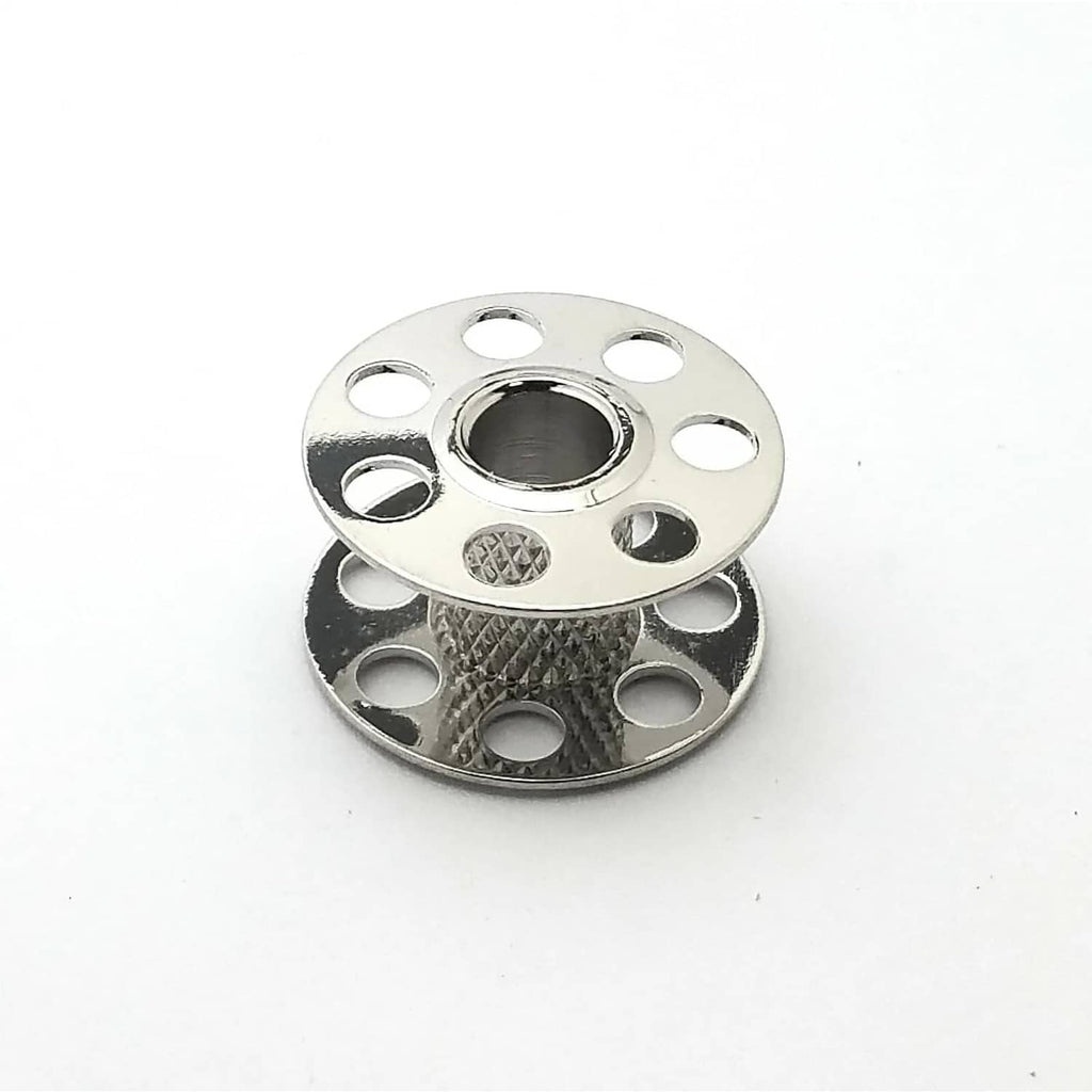 Single silver metal sewing bobbin with center hole, patterned base, and side cutouts