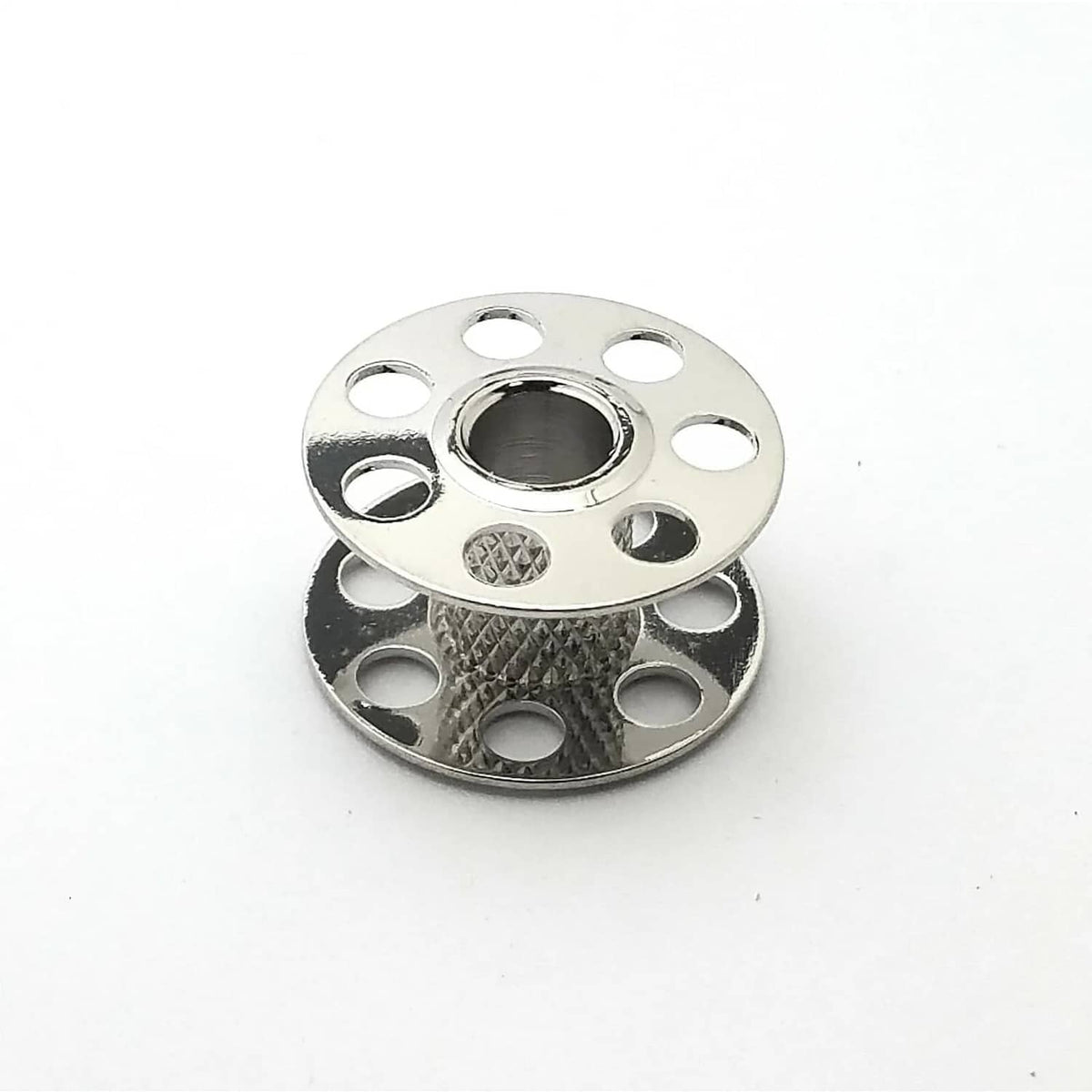 Single silver metal sewing bobbin with center hole, patterned base, and side cutouts