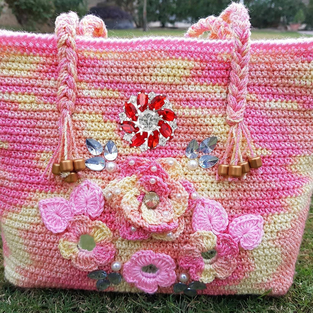 Crystal flower embellishment on a pink-and-yellow crocheted bag with red center stones