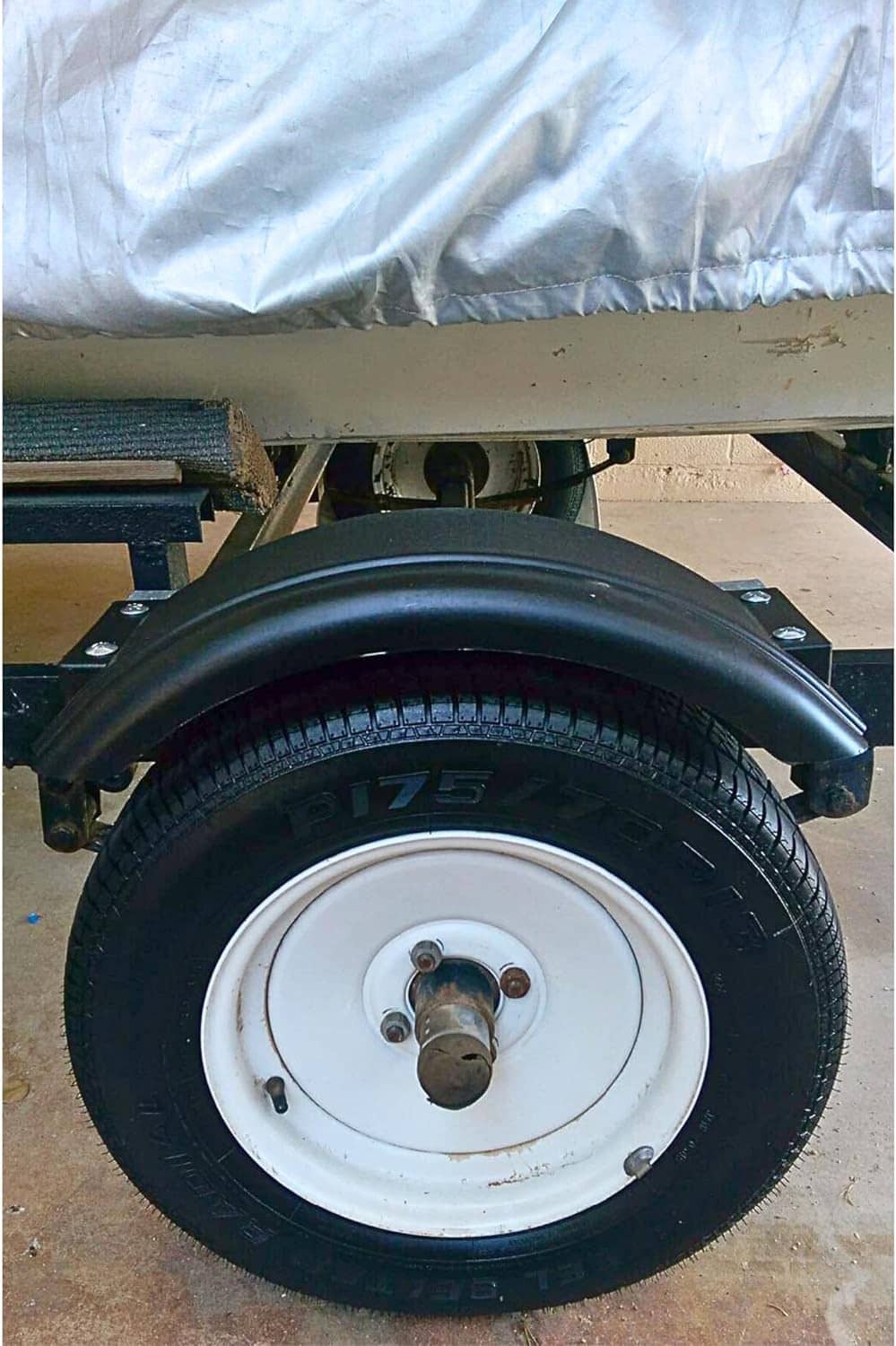Black trailer fender mounted above a wheel with visible mounting hardware
