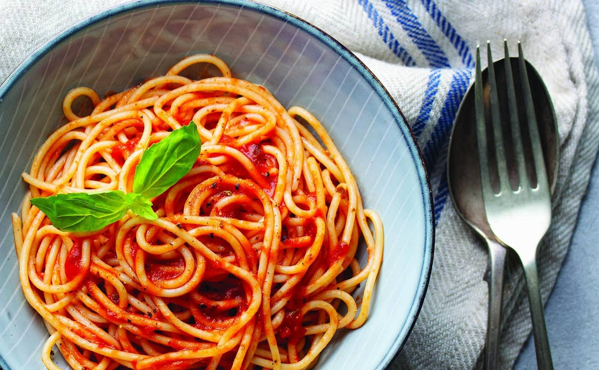 Spaghetti with Italian herb blend, red sauce strands and basil leaf garnish