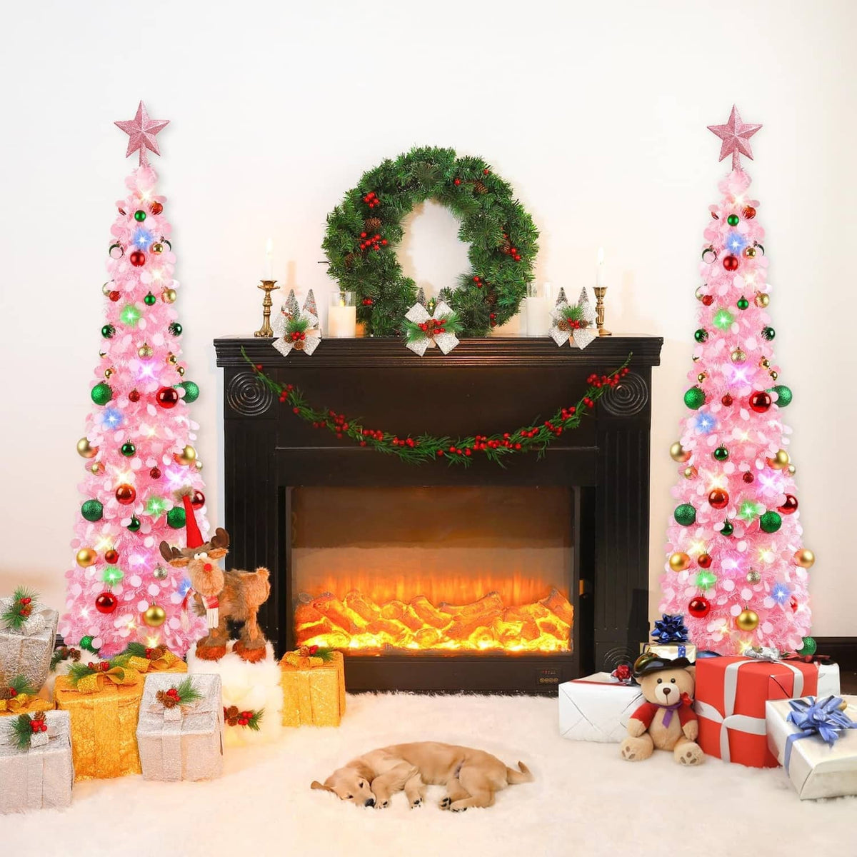 Two pink lit Christmas trees with star toppers, multicolor ornaments by fireplace