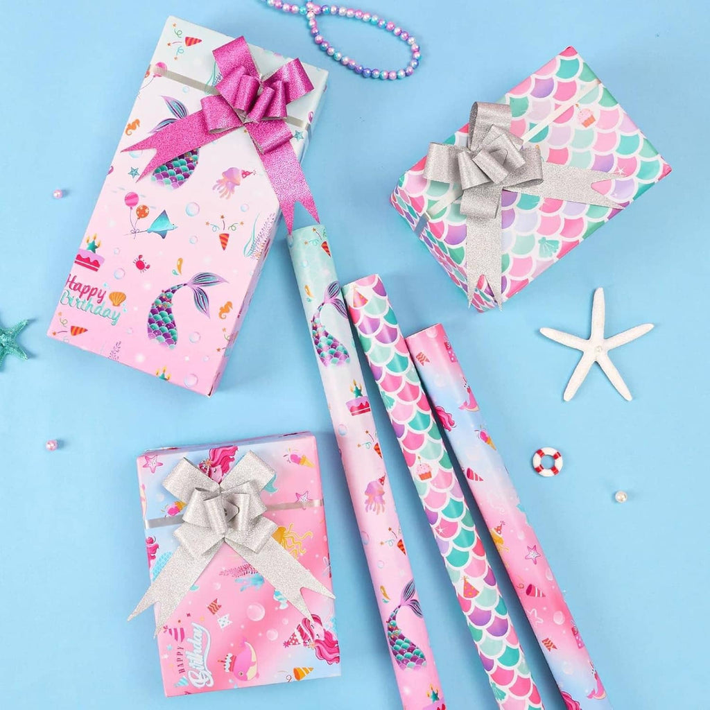 Gifts wrapped in mermaid scale and ocean-themed pink wrapping paper with bows