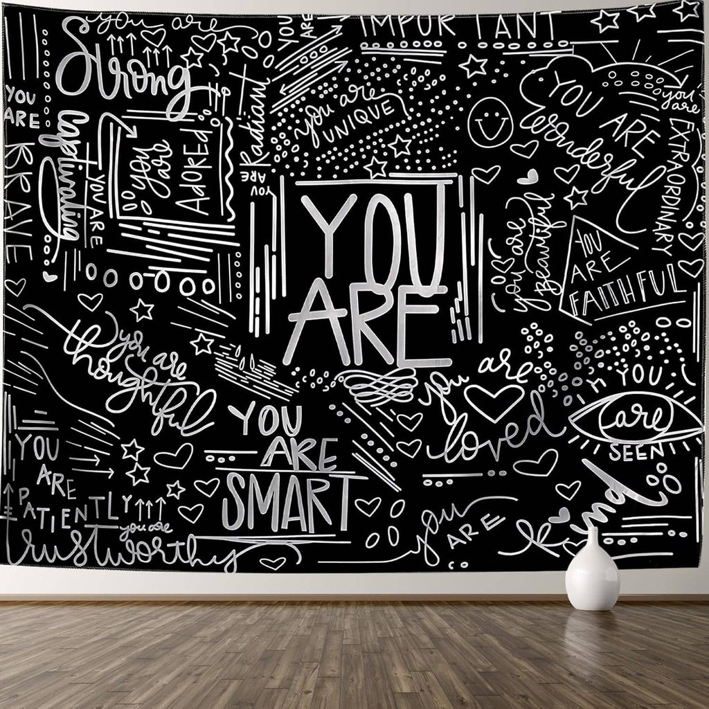 Black and white wall tapestry with YOU ARE quotes, stars, and heart doodles