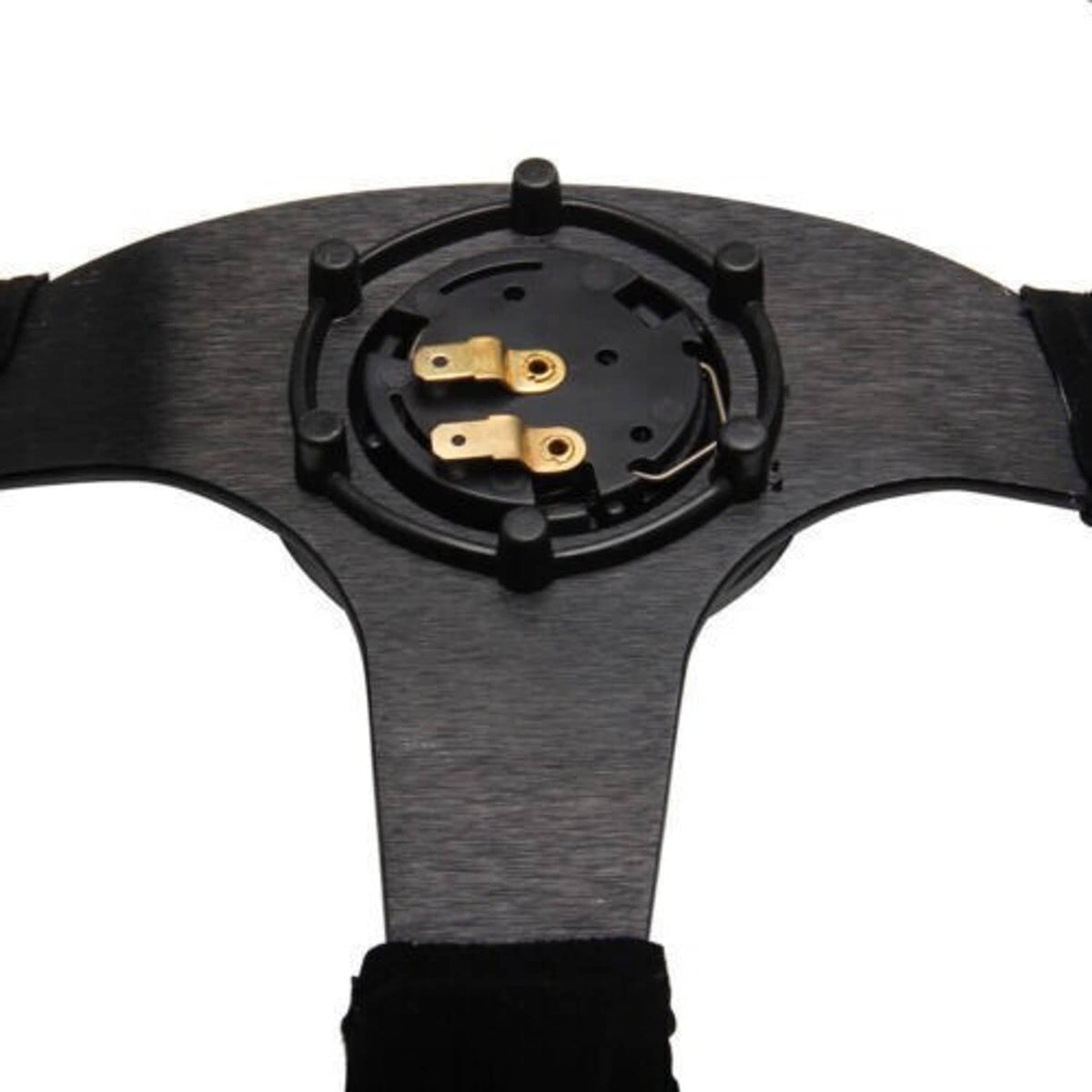 Close-up of steering wheel horn button area with gold contact terminals on black suede