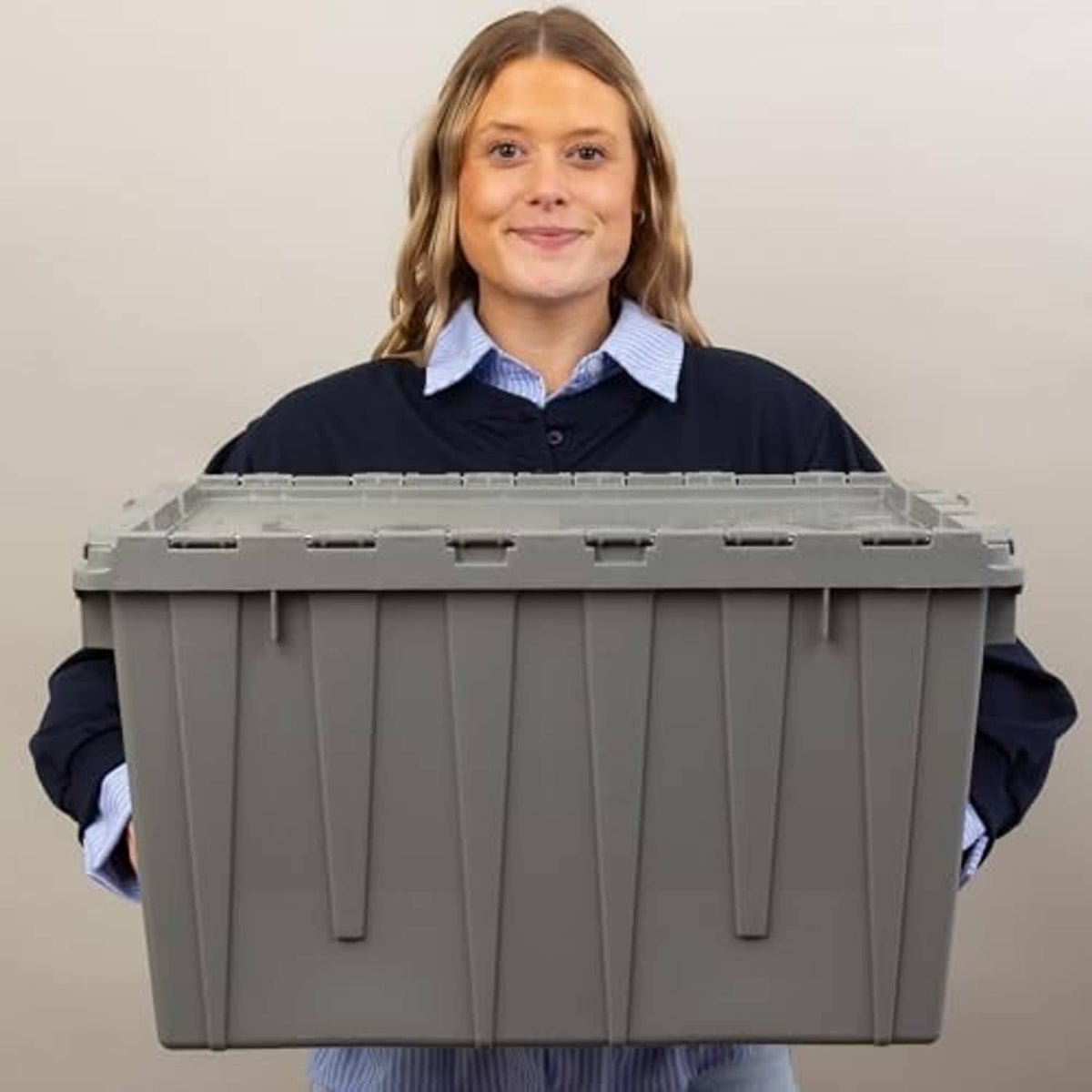 Grey plastic storage container with lidded top, held up for size