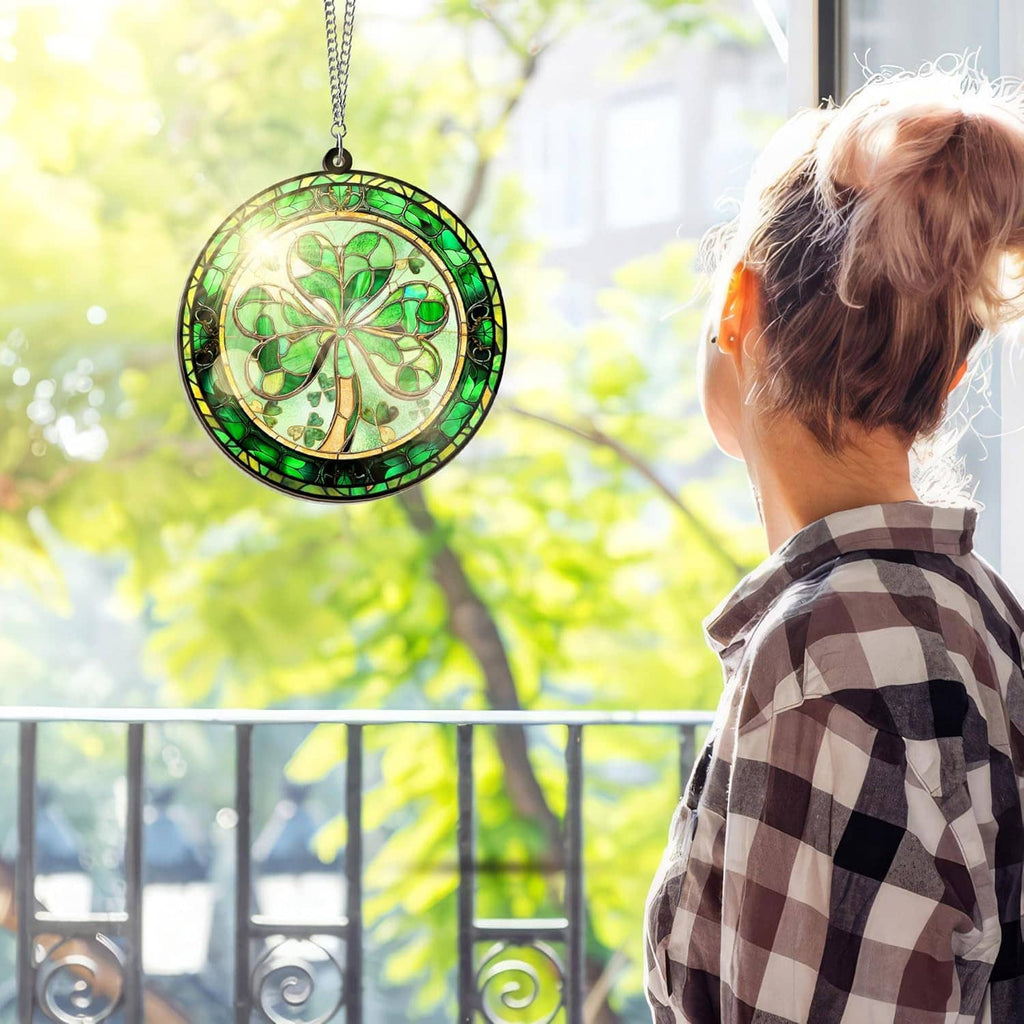 Round green shamrock stained-glass suncatcher hanging near window with silver chain