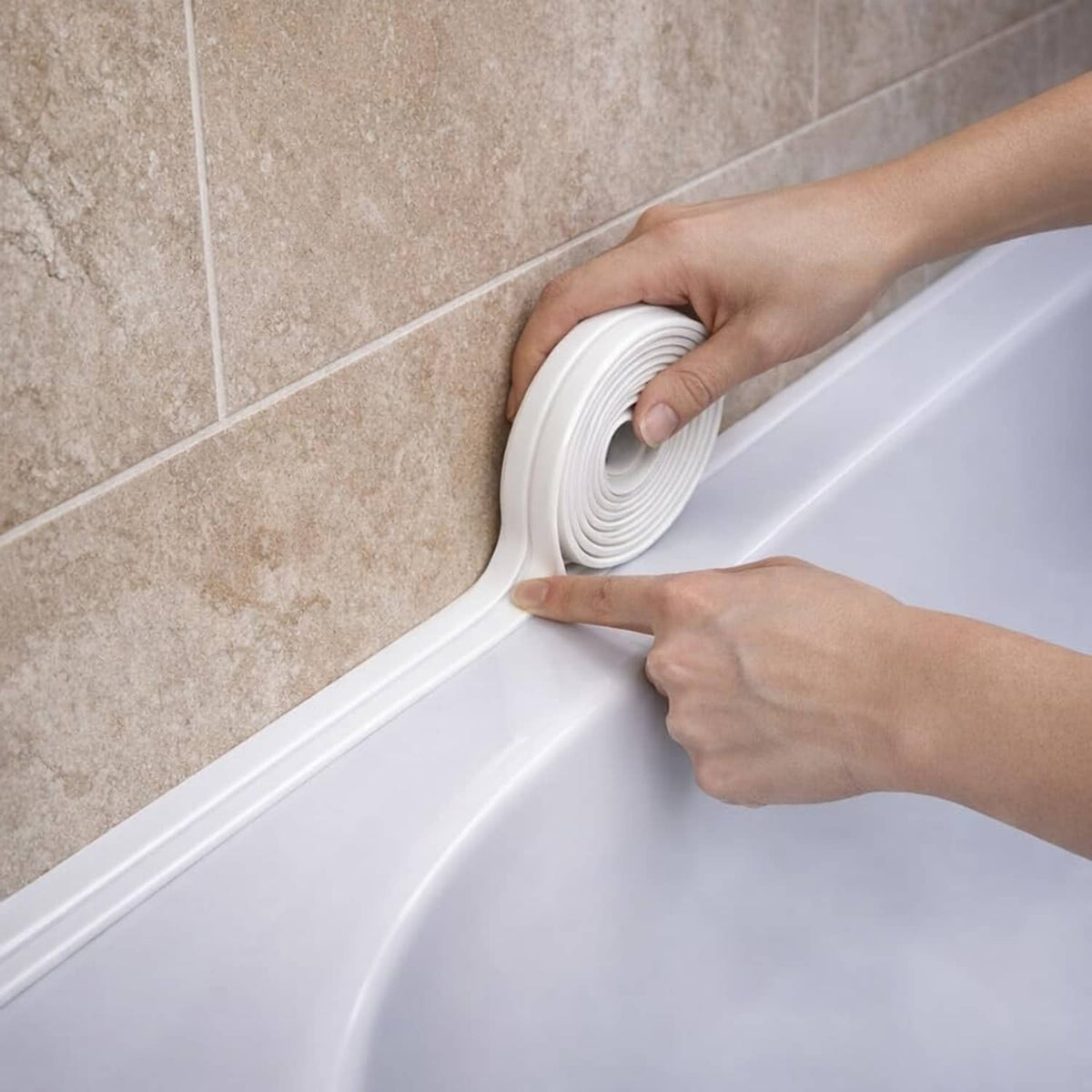 White self-adhesive waterproof caulk tape being applied along bathroom tub corner