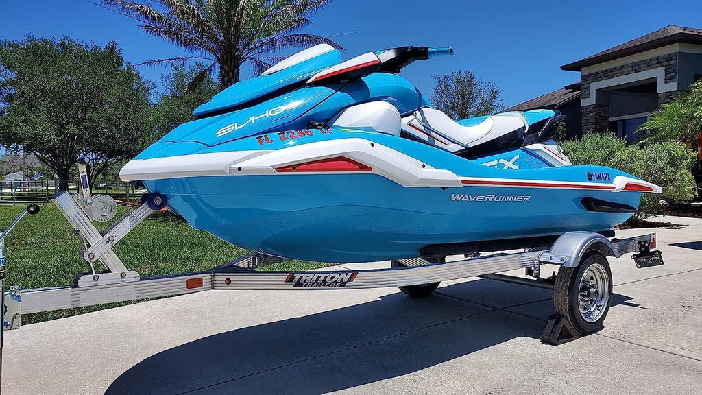 Blue and white jet boat with trailer, angled side view