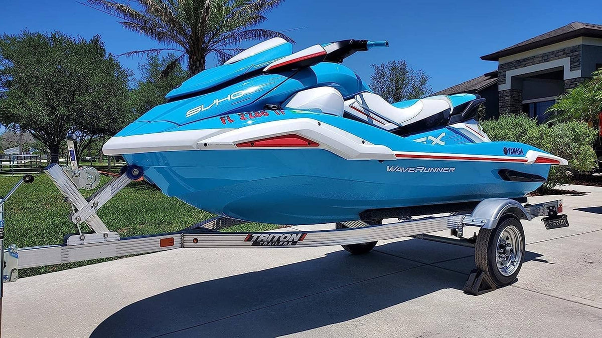 Blue and white jet boat with trailer, angled side view