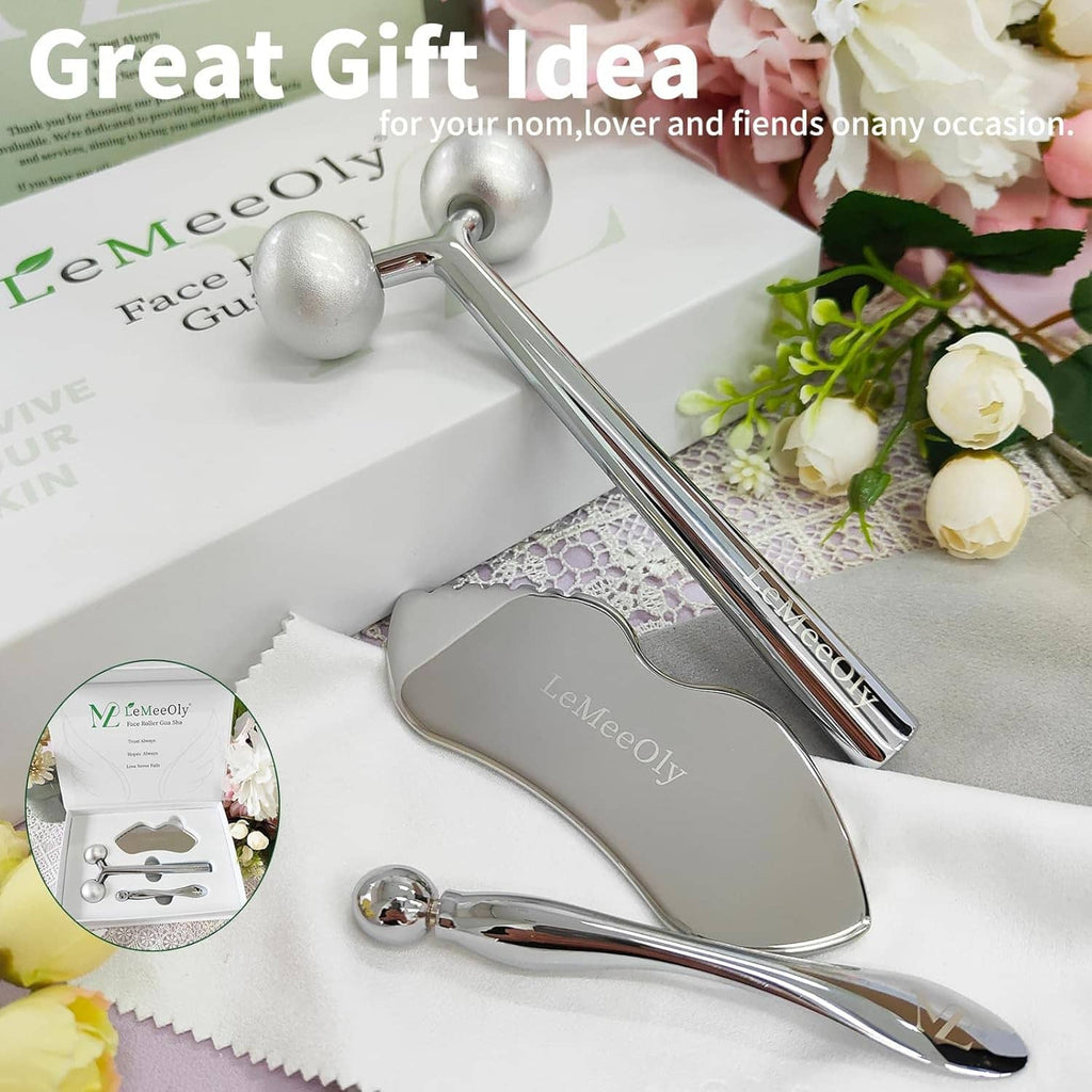 Silver stainless steel gua sha and face roller tools on a gift display, shiny finish
