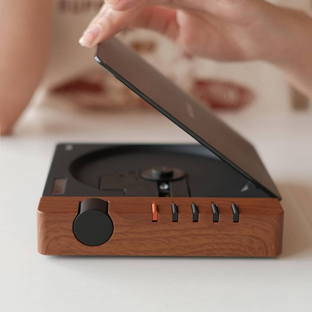 Portable CD player with wood base and black lid, close-up of side control sliders