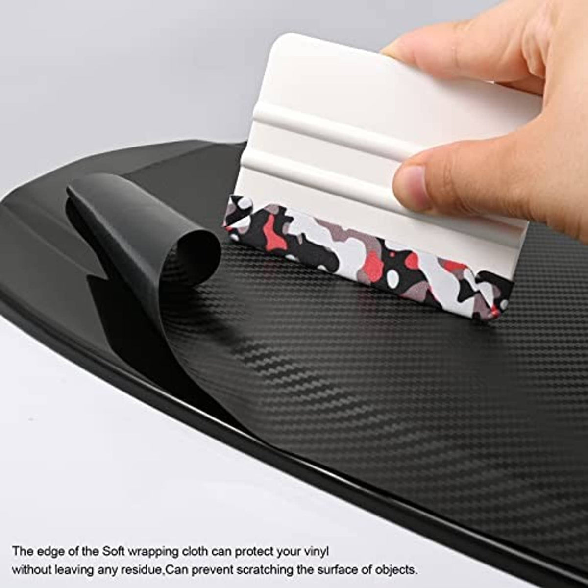 Hand using a white squeegee with camouflage felt edge on a dark textured vinyl surface