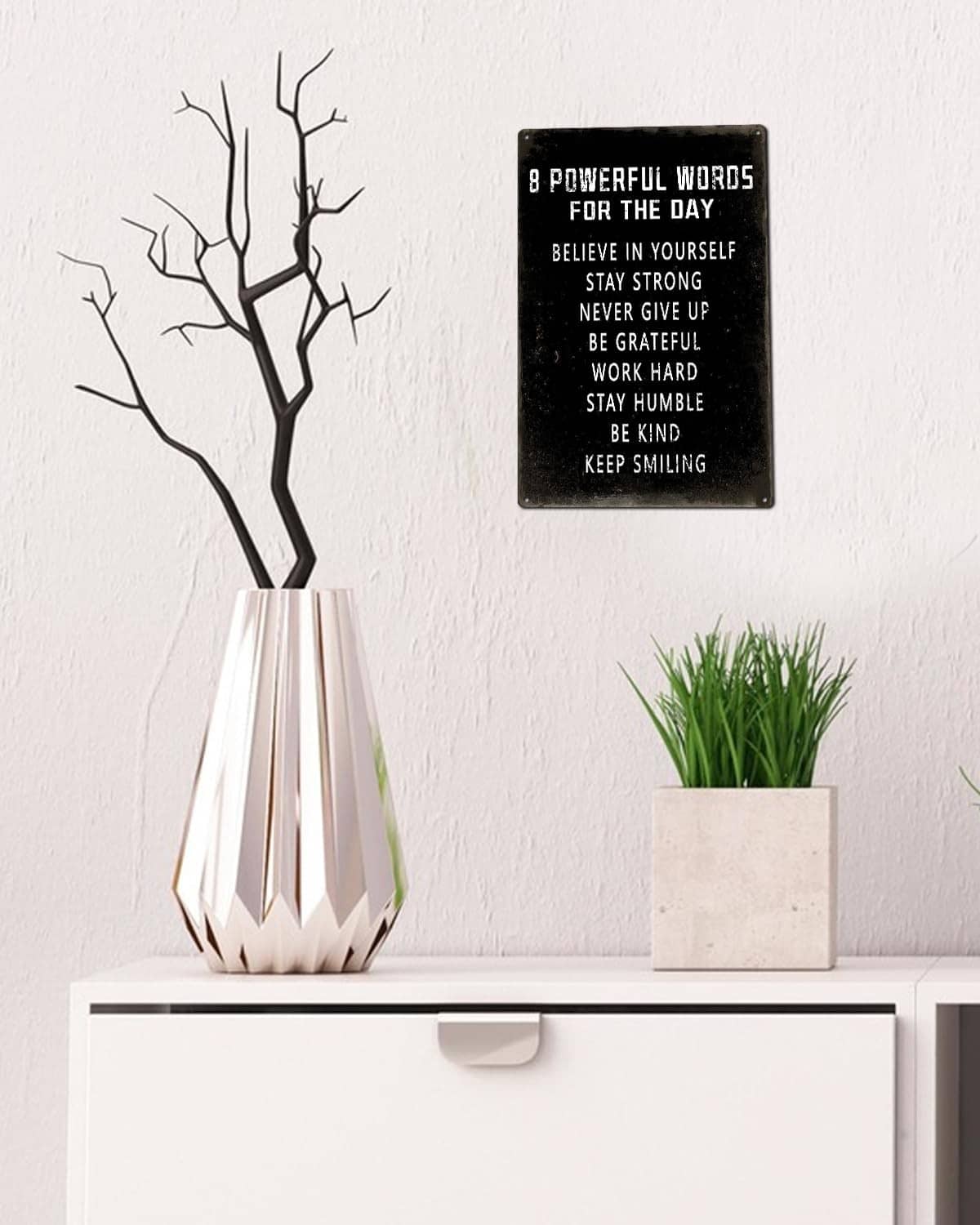 Black motivational wall sign with 8 phrases on a light-colored wall
