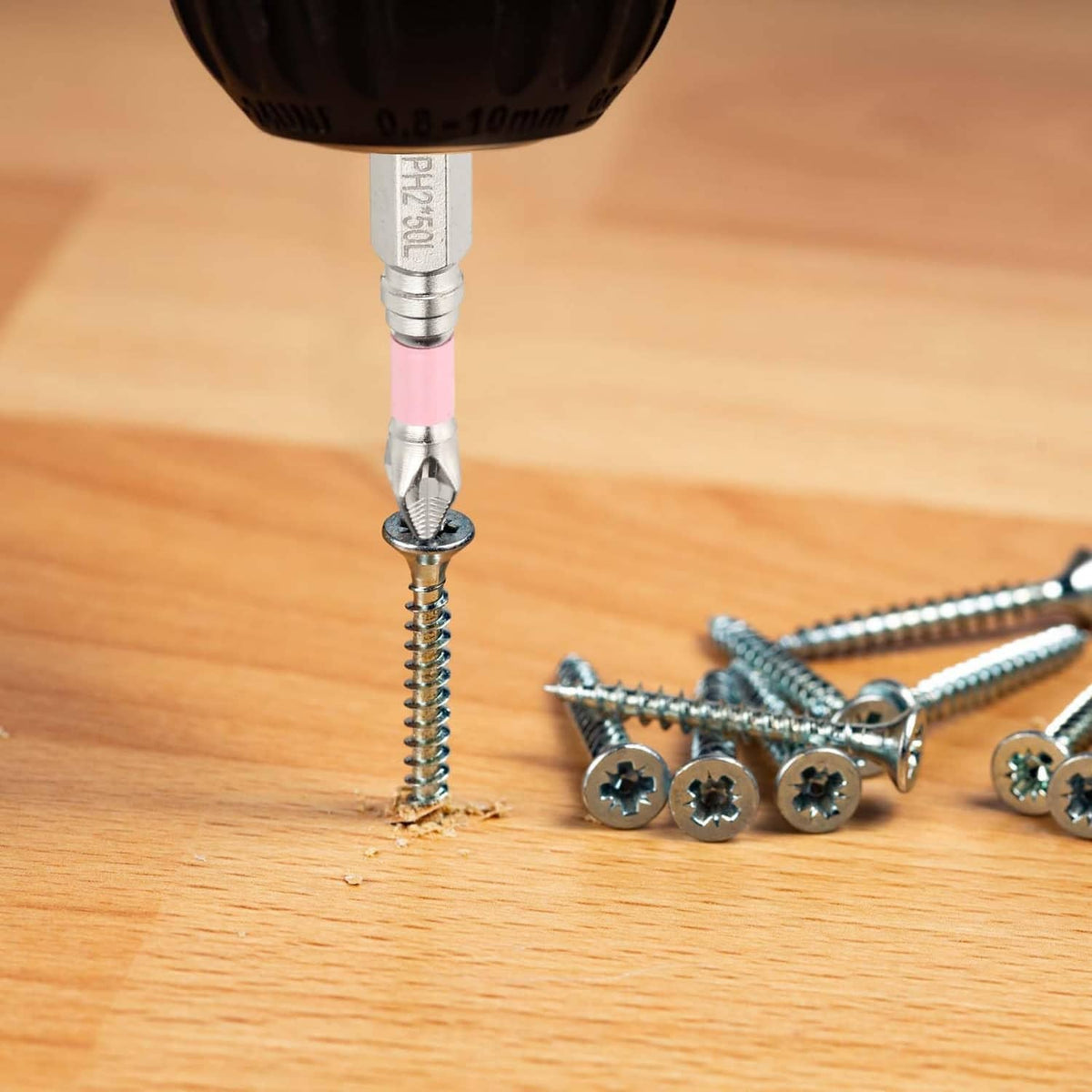 Phillips impact bit driving a screw into wood with pink shaft