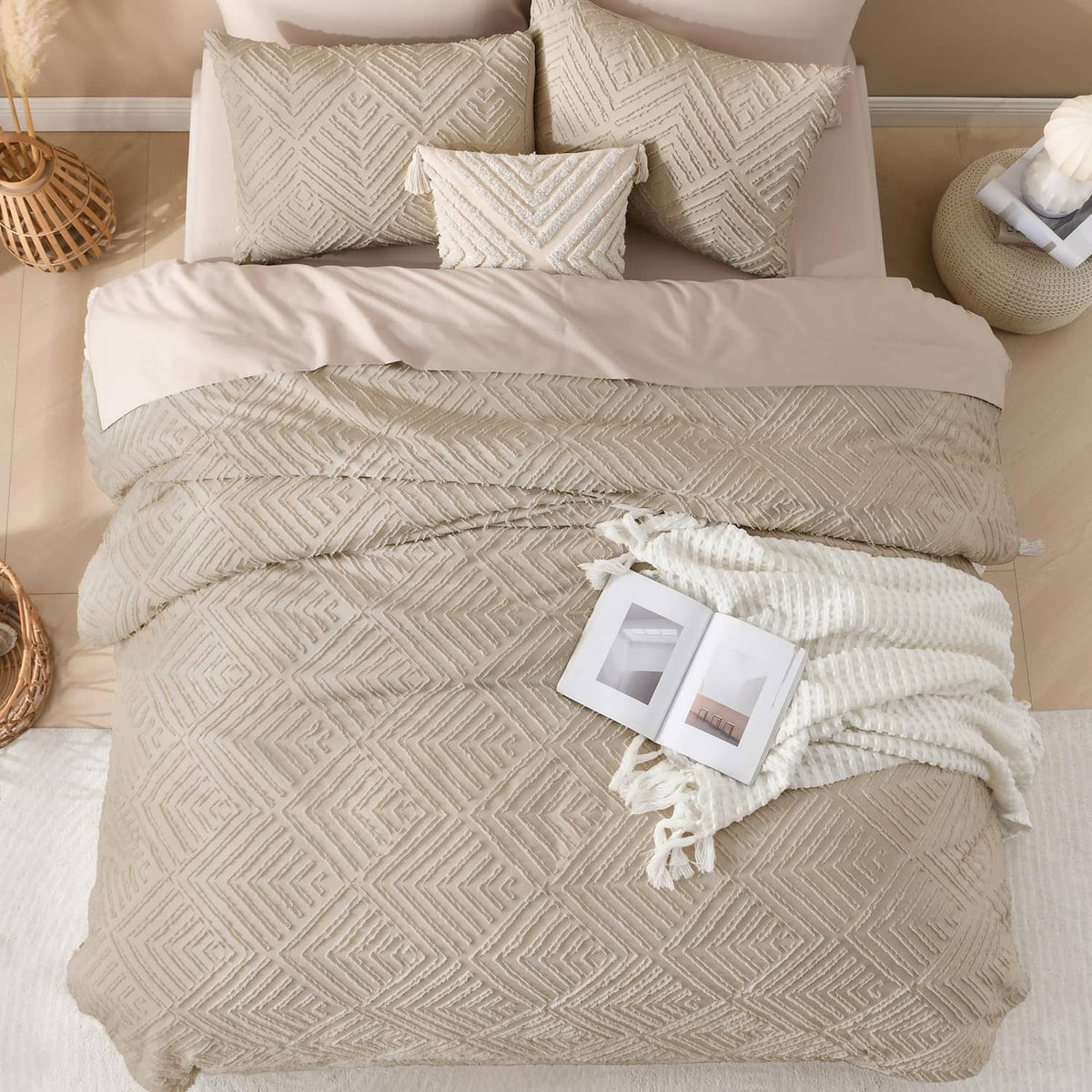 Light beige comforter set with geometric quilt pattern, decorative pillows, and fringed throw