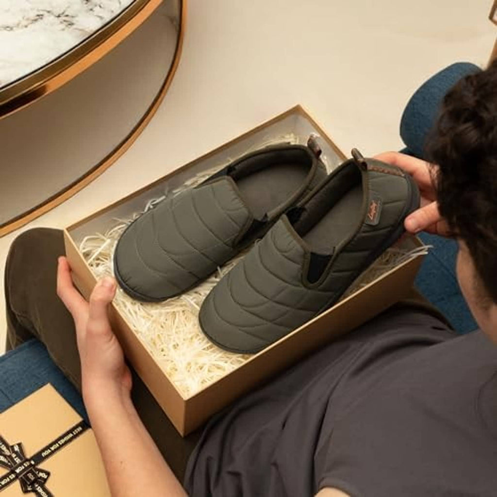 Pair of army green quilted slip-on slippers in box, showing padded collar and outsole