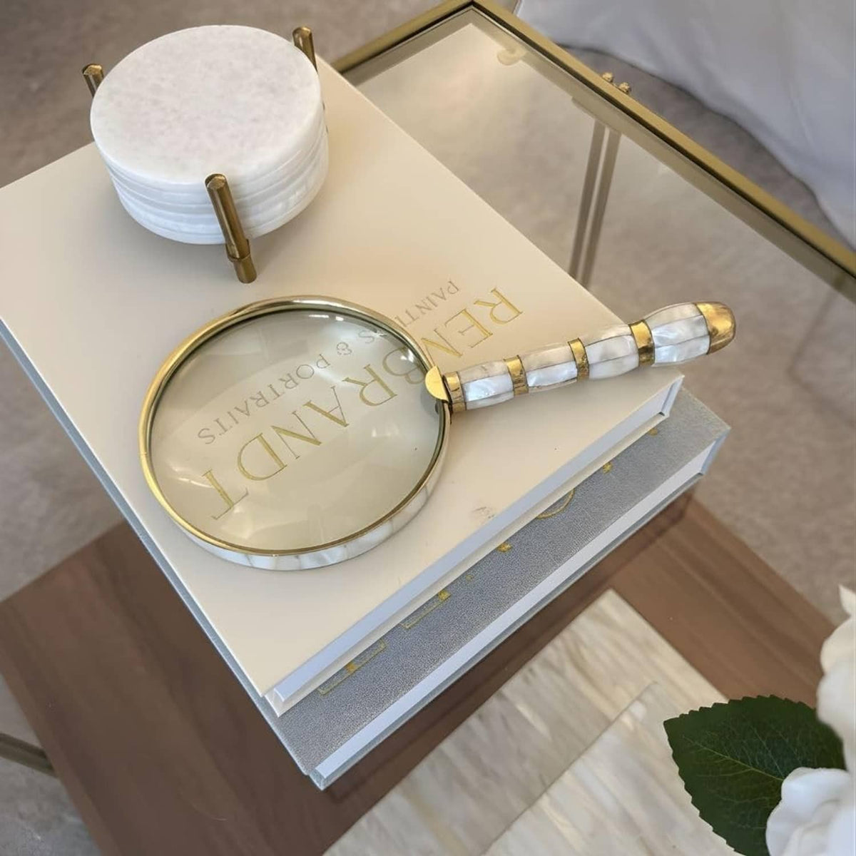 Round mother-of-pearl magnifier with gold rim and striped brass handle on gift box