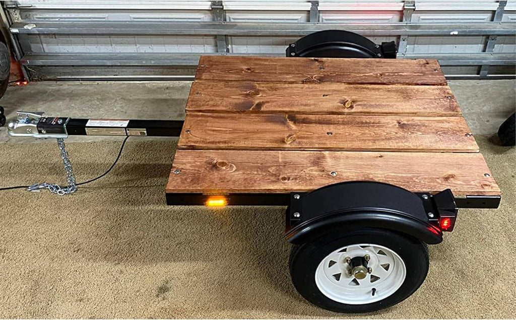 Black trailer fender with curved splash guard mounted beside a wheel