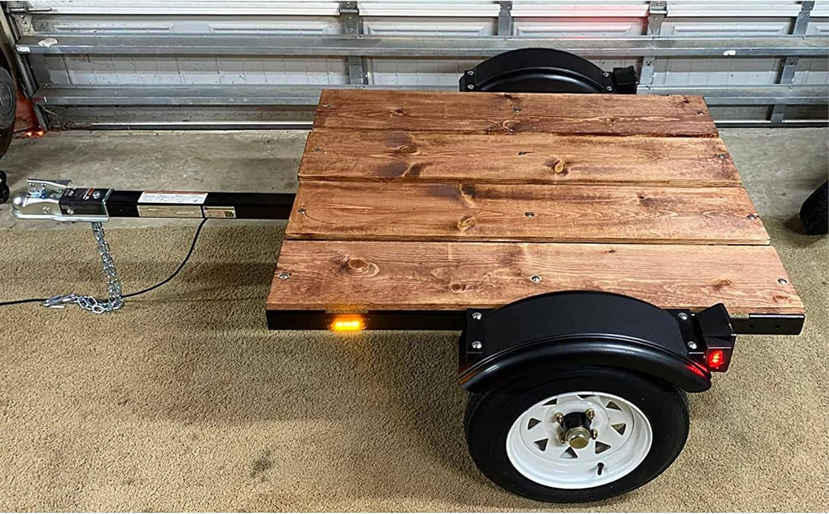 Black trailer fender with curved splash guard mounted beside a wheel