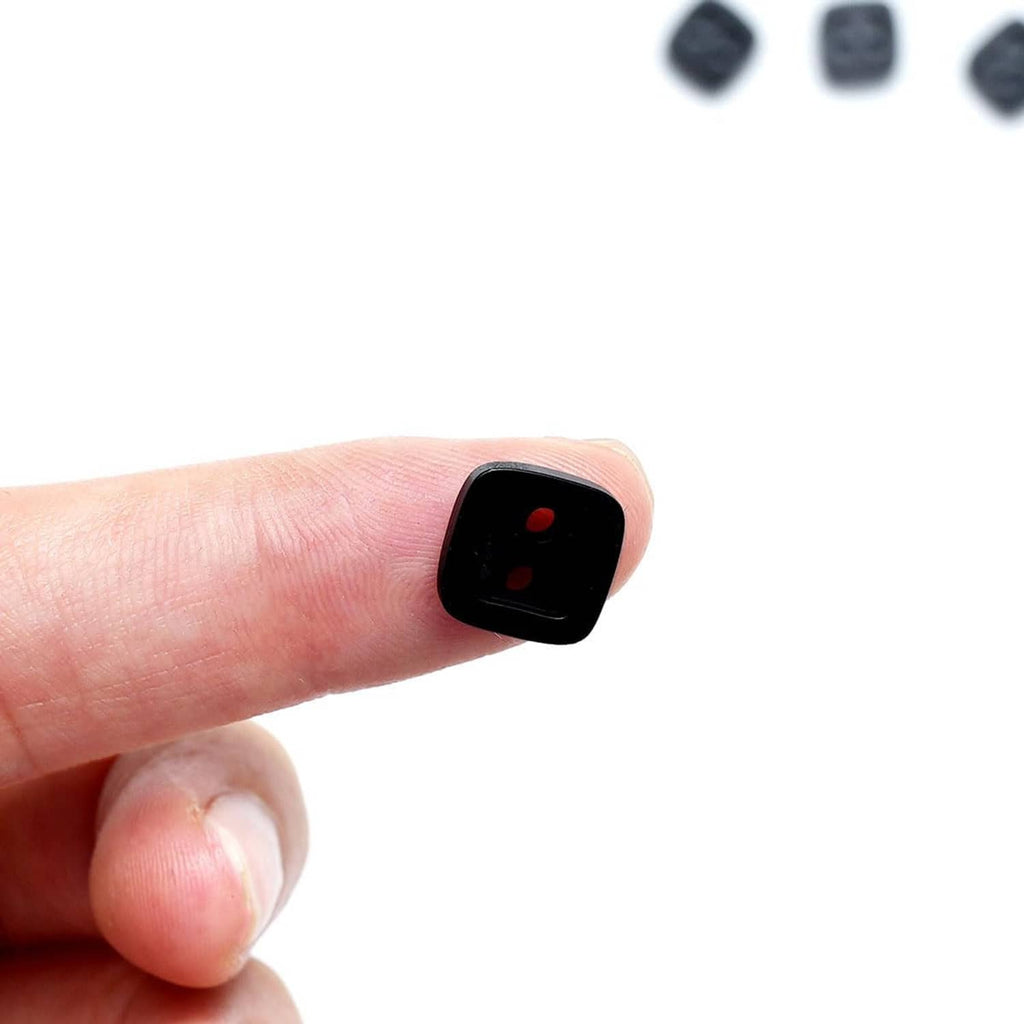 Black square 2-hole resin button held on fingertip, glossy front with two holes
